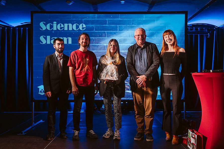 Bühne der Kulturfabrik den 5 Slammern in einer Reihe, in der Mitte steht die Siegerin mit dem Preis